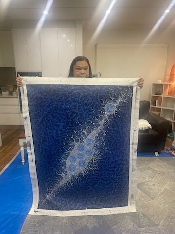 Nyrulla Possum holding her seven sisters artwork