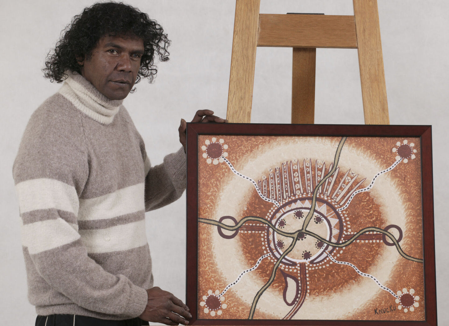 Lewis Langton standing with his artwork of Canberra in natural ochre